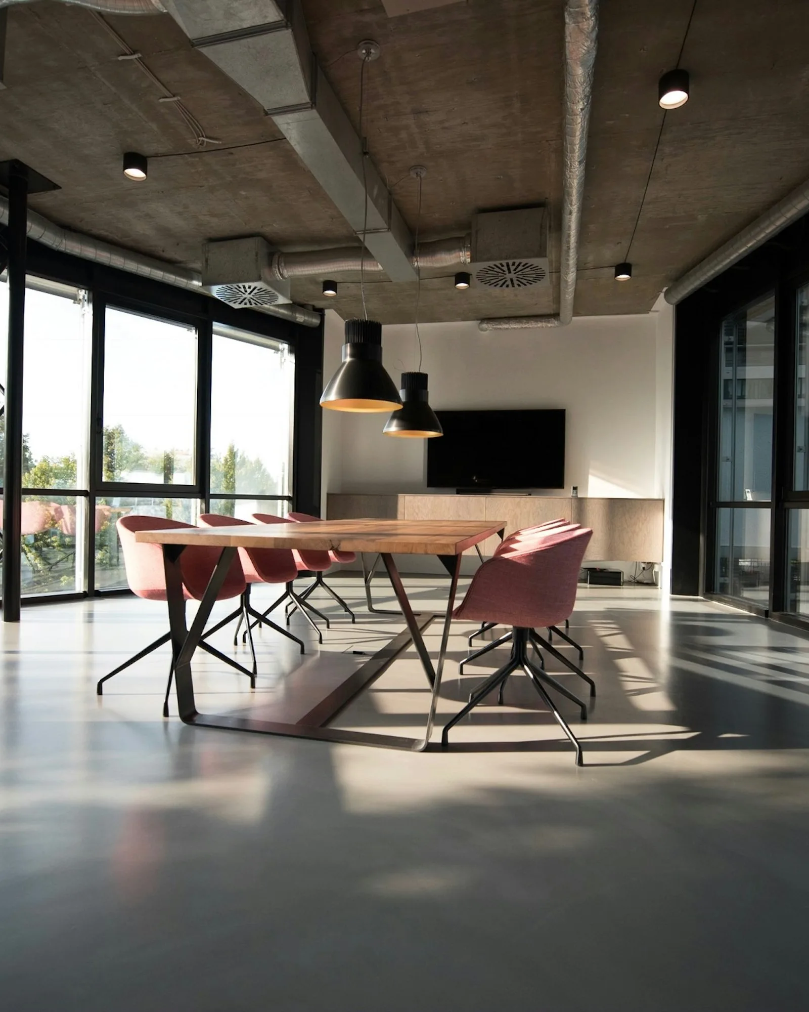 Sunlit glass meeting room looking onto a quiet studio floor